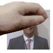 a hand is holding a picture of a man in a suit and tie and smiling .
