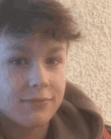a close up of a young boy 's face with a gray hoodie on