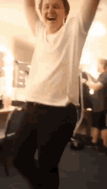 a man in a white shirt and black pants is jumping in the air with his arms in the air .