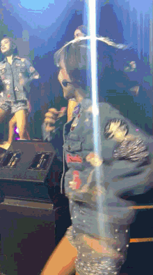 a woman in a denim jacket is holding a microphone in front of a crowd