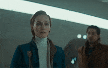 a woman in a blue jacket is standing next to a man in a brown jacket with the word kepler on the bottom