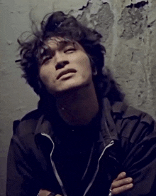 a man in a black jacket with his arms crossed looks up