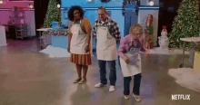 a group of people wearing aprons are dancing in a room with christmas trees in the background .