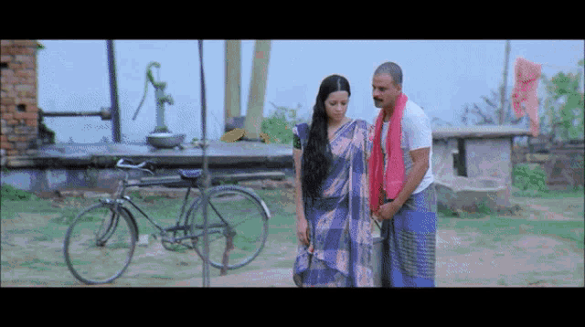 a man and a woman standing next to each other in front of a bicycle