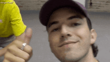 a man wearing a hat and a ring gives a thumbs up