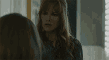 a woman with red hair is looking at herself in the mirror .