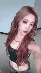 a woman with long red hair is taking a selfie while wearing a crop top and jeans .