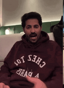 a man wearing a maroon sweatshirt that says chess 101