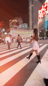 a woman in a pink dress is crossing a street with a sign that says ' strawberry '