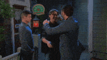 a man in a plaid shirt hugging another man in a suit