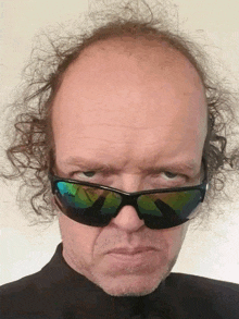 a bald man wearing sunglasses is making a face