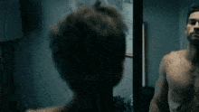 a man is looking at his hair in the mirror .