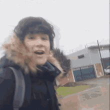 a person wearing a black jacket with a fur hood and a backpack .