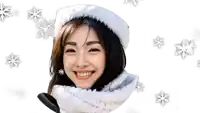 a woman is wearing a santa hat and scarf and smiling while snowflakes fall around her .