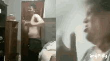a man without a shirt is standing in front of a mirror in a room .