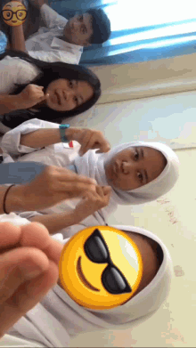 a girl wearing sunglasses has a smiley face on her face in front of her