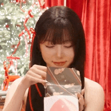 a woman with long black hair is opening a christmas present .