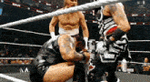 a wrestler is kneeling down in a wrestling ring while another wrestler looks on