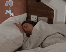 a woman sleeping in a bed with the letters n and n written on the wall behind her