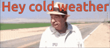 a man wearing a hat is standing on the side of a road with the words hey cold weather written above him