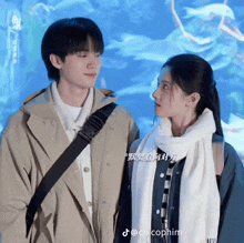 a man and a woman are looking at each other in front of an aquarium with chinese writing