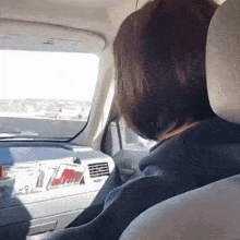 a woman is driving a car and looking out the window at the road