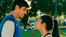 a man and a woman are looking at each other and kissing in a park .