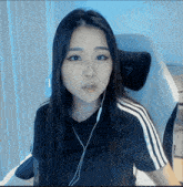 a woman wearing a black shirt with white stripes on the sleeves looks at the camera