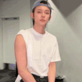 a young man wearing a white tank top and a baseball cap