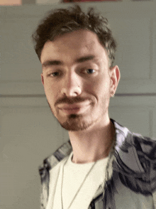a man with a beard is wearing a white shirt and a necklace