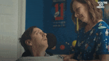 a man in a wheelchair is talking to a woman who is holding a bottle and says you 're my hero