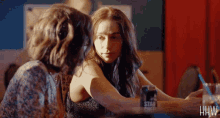 two women are sitting at a table with a can of star cheers on it