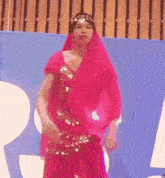 a woman in a pink dress is standing in front of a blue wall .