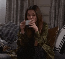 a woman sits on a couch drinking from a mug that says coca cola