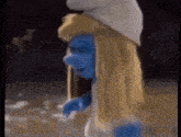 a smurf with long blonde hair and a white hat is standing in the dark .