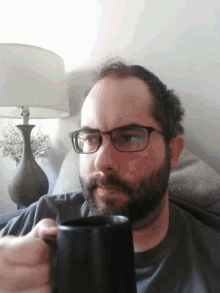 a man with glasses is holding a black mug