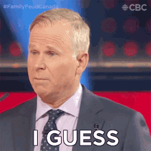 a man in a suit and tie says i guess in front of a microphone