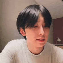 a young man with short black hair is wearing a white t-shirt .