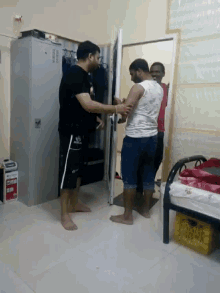 a group of men are standing in a room and one of them is wearing a shirt that says ' a ' on it