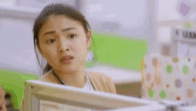a woman is sitting at a desk in front of a computer screen .