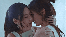 a couple of women are kissing each other on the forehead .