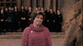a woman in a pink sweater is standing in front of a group of children