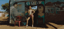 a woman stands in front of a building with kliptown painted on it