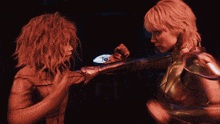 two women are fighting each other in a dark room and one is wearing armor
