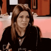 a woman is sitting at a table with a glass of water and a plate of food .