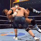 two men are wrestling in a ring and one of them is wearing a pair of socks that say ' r ' on it