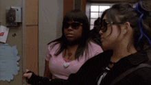 two girls wearing sunglasses are standing next to each other in front of a door