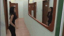 a woman stands in front of a large mirror in a hallway
