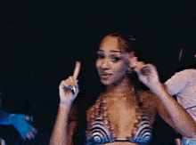 a woman in a bikini is standing in front of two other women in bikinis .