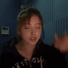 a woman covering her face with her hand and wearing a hoodie that says abercrombie & fitch
